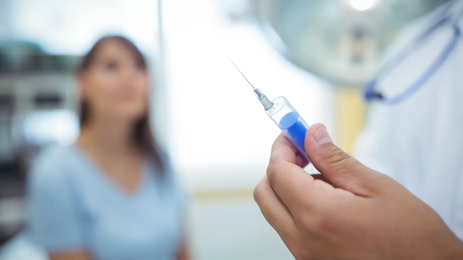 Ein verschwommener Hintergrund, im Fokus eine Spritze.