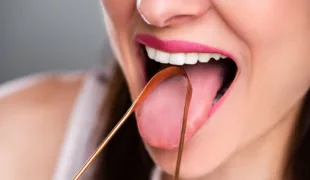 Frau reinigt ihre Zunge mit Reiniger