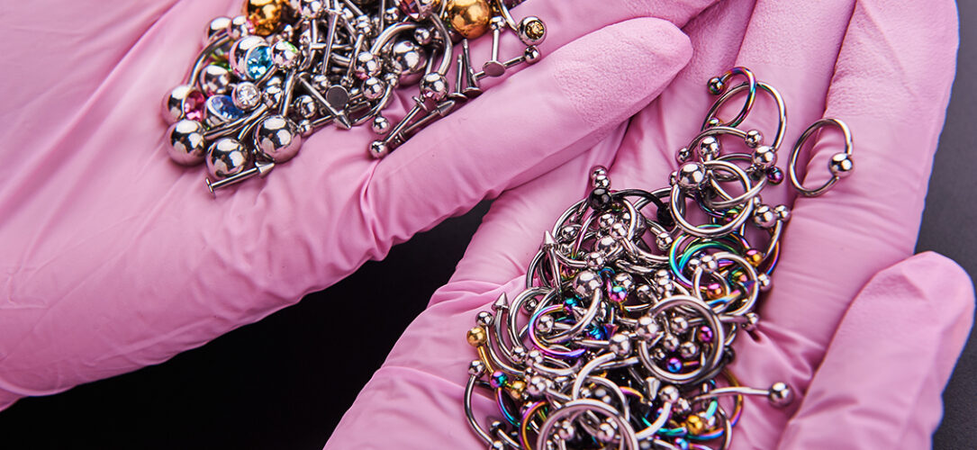Hände in rosa Medizinhandschuhen halten viele Piercings