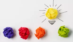 in verschiedenen Farben zerknülltes Papier, das gelbe wurde zu einer leuchtenden Glühbirne als Idee