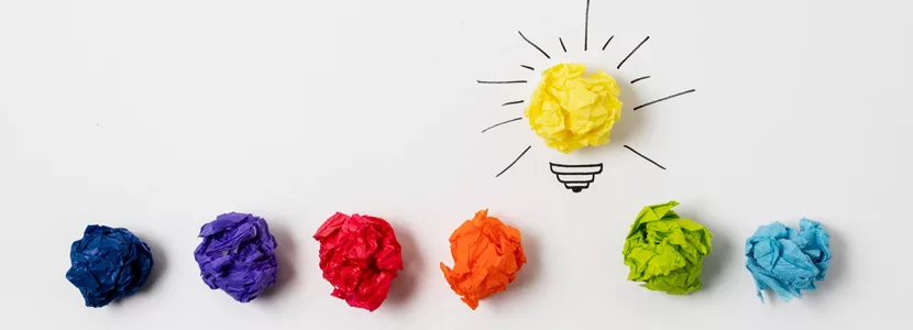 in verschiedenen Farben zerknülltes Papier, das gelbe wurde zu einer leuchtenden Glühbirne als Idee