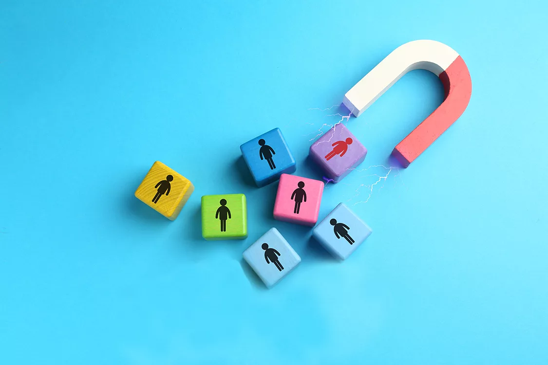 Magnet attracting colorful cubes with human figures on light blue background, top view. Recruitment or customer acquisition