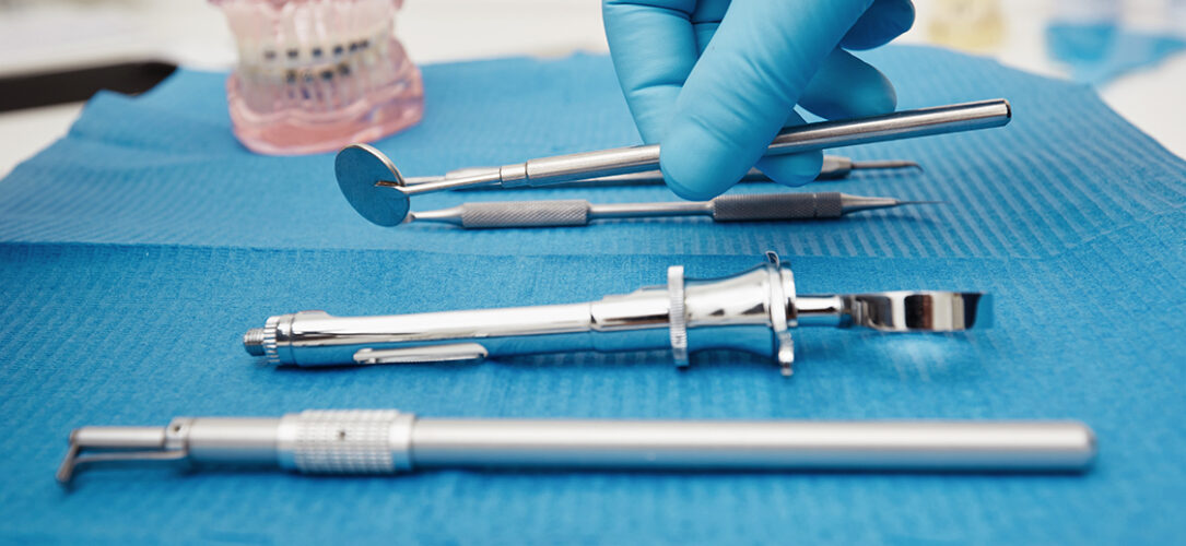 Set of metal medical equipment tools for teeth dental care. Doctor takes medical instruments. Hand of dentist reaching for dental instruments in a cabinet