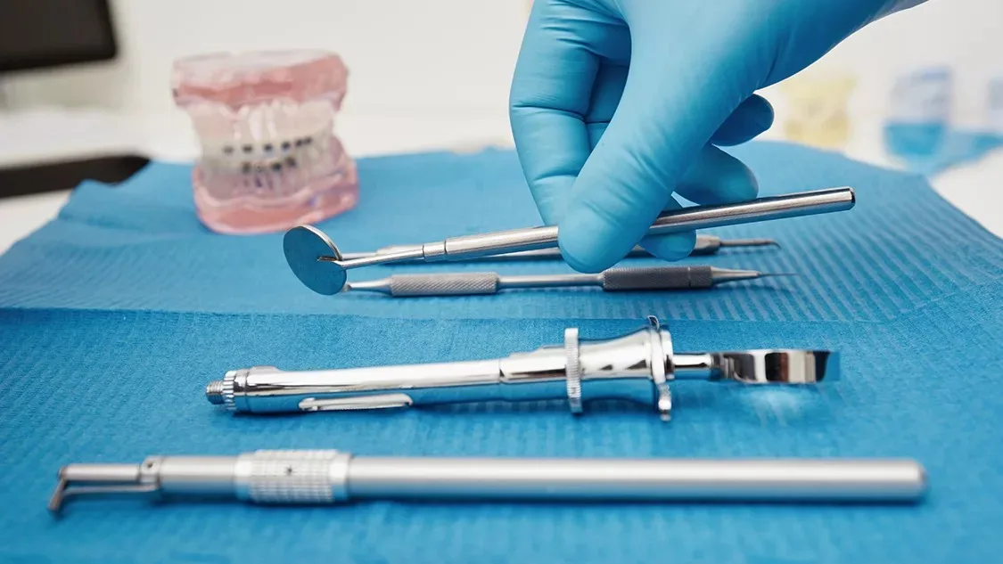 Set of metal medical equipment tools for teeth dental care. Doctor takes medical instruments. Hand of dentist reaching for dental instruments in a cabinet