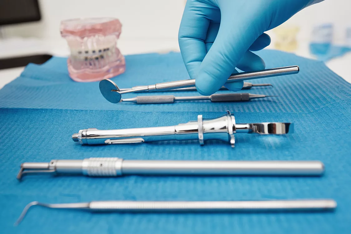 Set of metal medical equipment tools for teeth dental care. Doctor takes medical instruments. Hand of dentist reaching for dental instruments in a cabinet