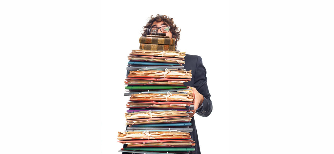 Mann, der viele Bücher, Ordner und Unterlagen trägt. young employee