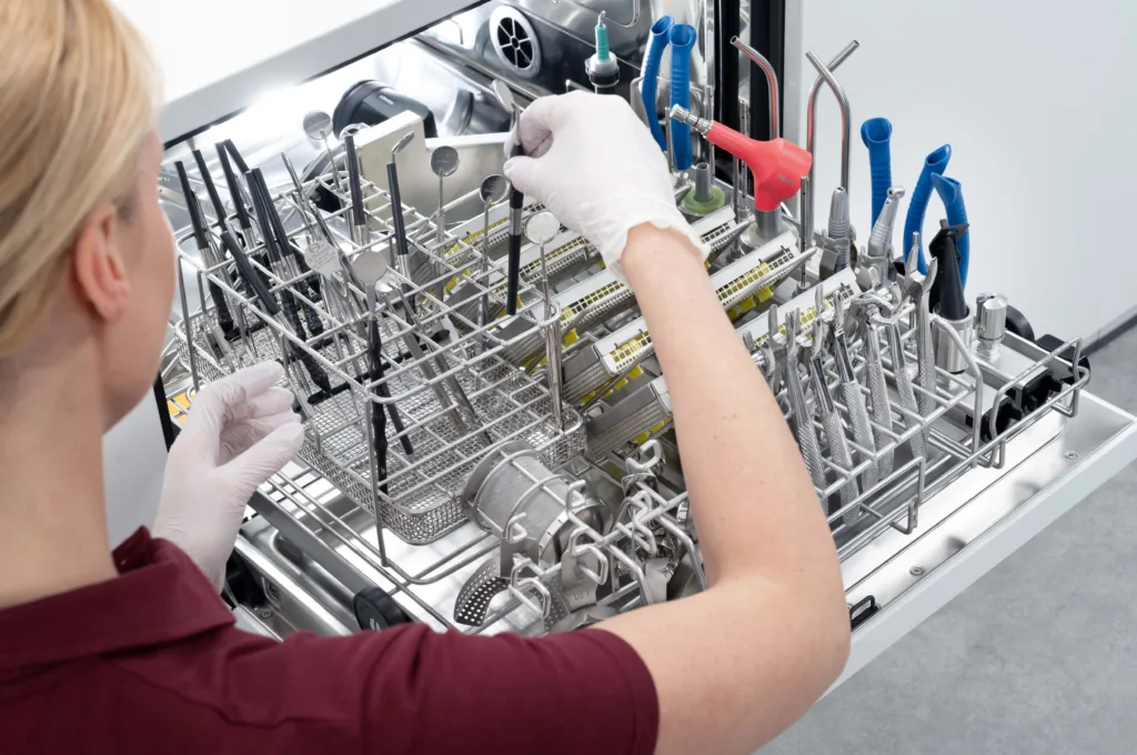 Mitarbeiterin an einem Reinigungs- und Desinfektionsgerät der CompactLine von Miele.