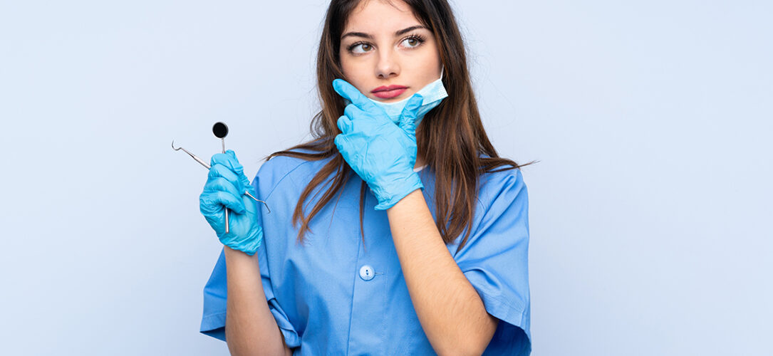 Woman dentist holding tools over isolated blue background thinking an idea