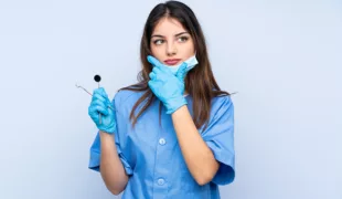 Woman dentist holding tools over isolated blue background thinking an idea