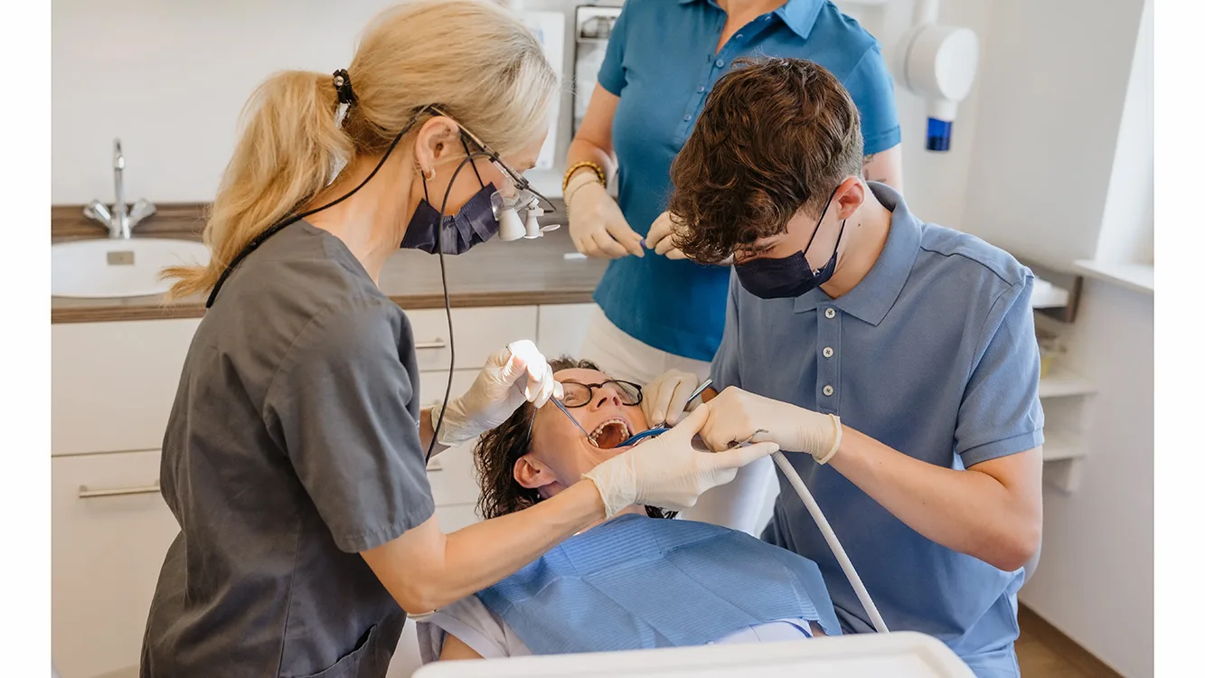 Zahnärztin mit Helfer am Patienten