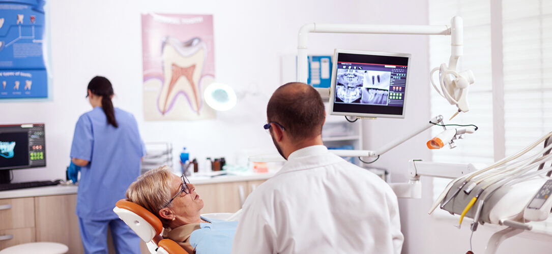 Senior woman discussing with dentist in dental cabinet about teeth issue sitting on chair. Medical teeth care taker discussing with senior woman about mouth hygiene.