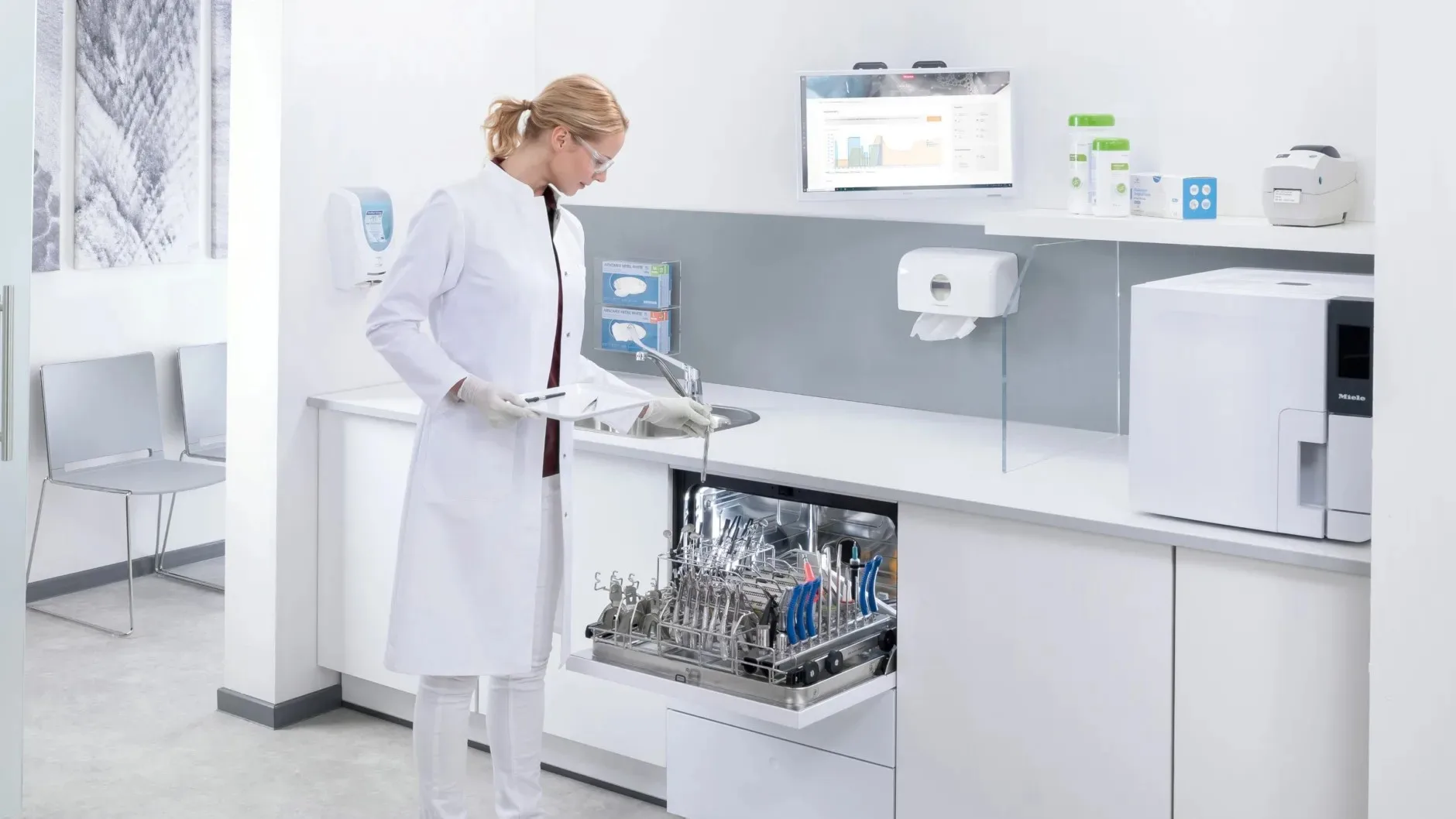 Mitarbeiterin räumt ein Reinigungs- und Desinfektionsgerät der CompactLine von Miele ein.