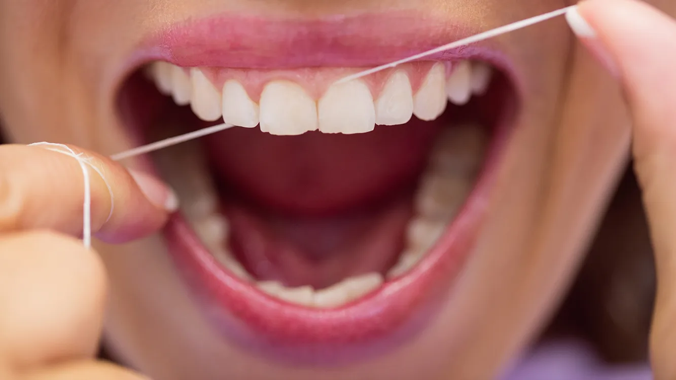 Close-up of female patient flossing her teeth in dental clinic