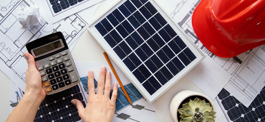 Solarzellen, Taschenrechner, roter Helm, Unterlagen zur Planung auf einem Tisch