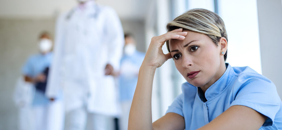Worried nurse taking a break and contemplating while sitting in a lobby at medical clinic.