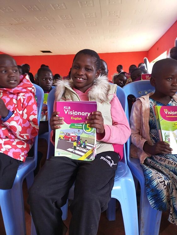 Ein Mädchen, welches stolz ihr Schulheft zeigt.