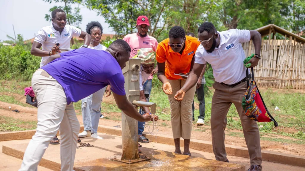 Fünf schwarze sind an ihrem neuen Brunnen und freuen sich über ihr Wasser.