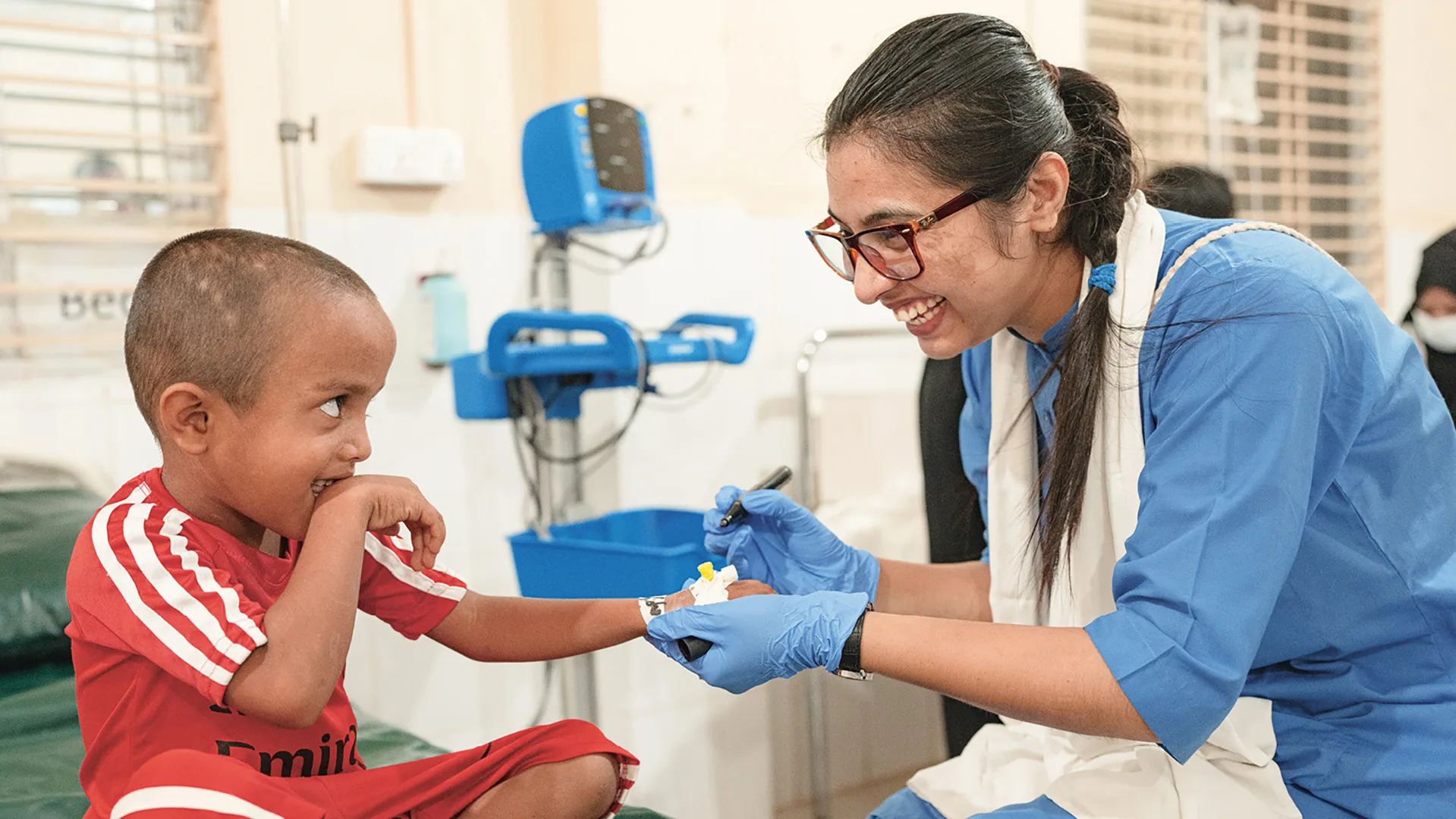 Eine fröhliche Interaktion in einem Behandlungszimmer zwischen einem Kleinkind und ärztlichem Personal.