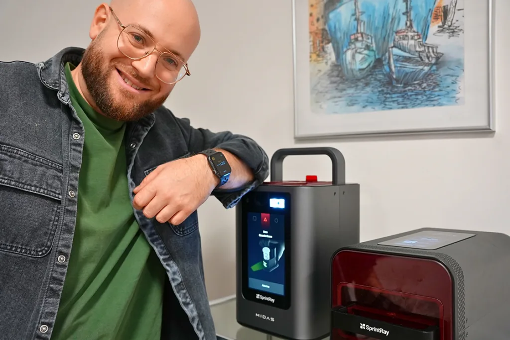 Freundlicher Mann lehnt am SprintRay Midas 3D-Drucker