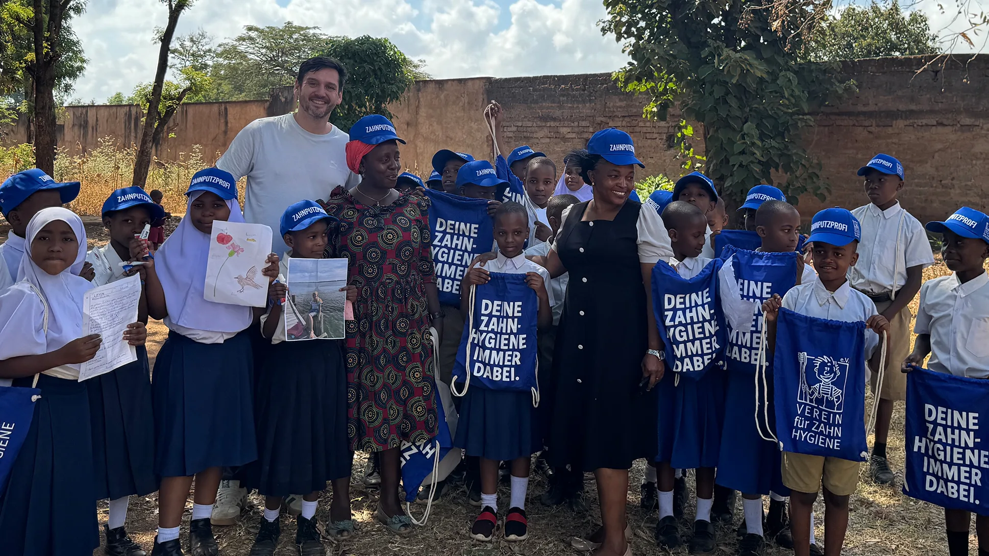 Wolfgang Dezor, Vorstandsvorsitzender des Vereins für Zahnhygiene e.V., (im Hintergrund) mit Schülerinnen und Schülern der Karanga Primary School in Moshi