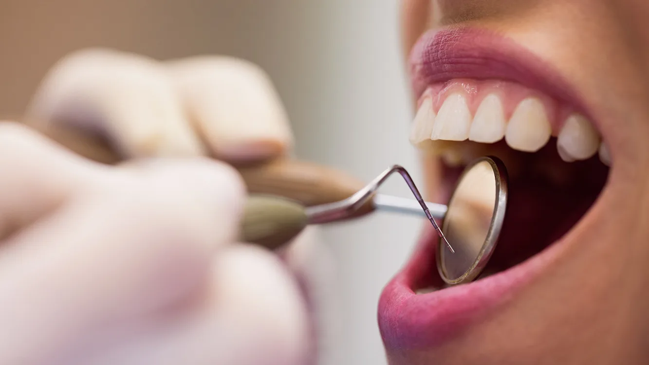 Close-up of dentist examining a female patient with tools at dental clinic