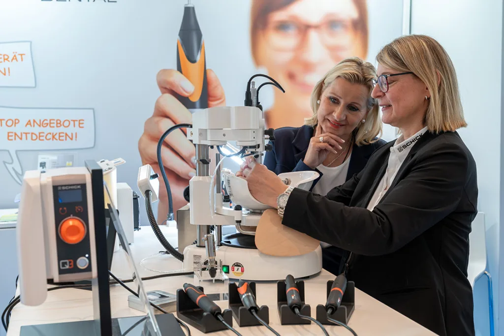 Zwei Frauen betrachten neue Geräte an einem Messestand