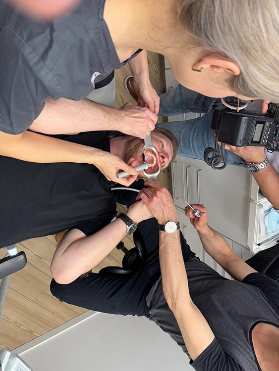 die Zähne eines Mannes werden mit Instrumenten sichtbar gemacht (der Mund wird aufgehalten)