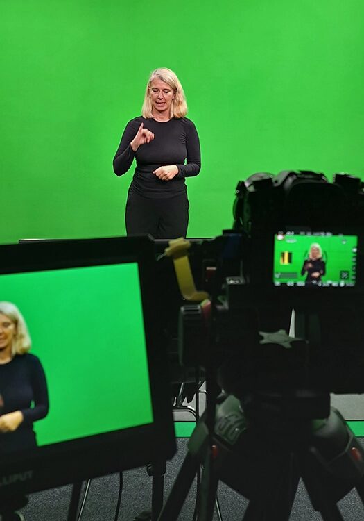 Frau steht vor einem grünen Hintergrund.