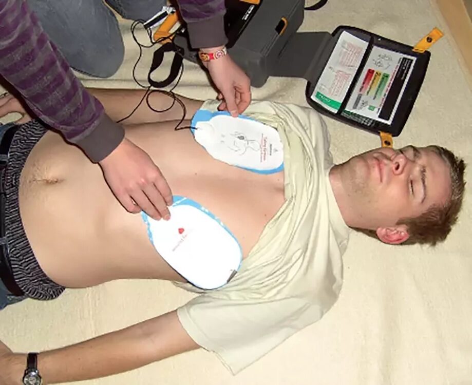 Ein Mann liegt am Boden  und wird defibrilliert 