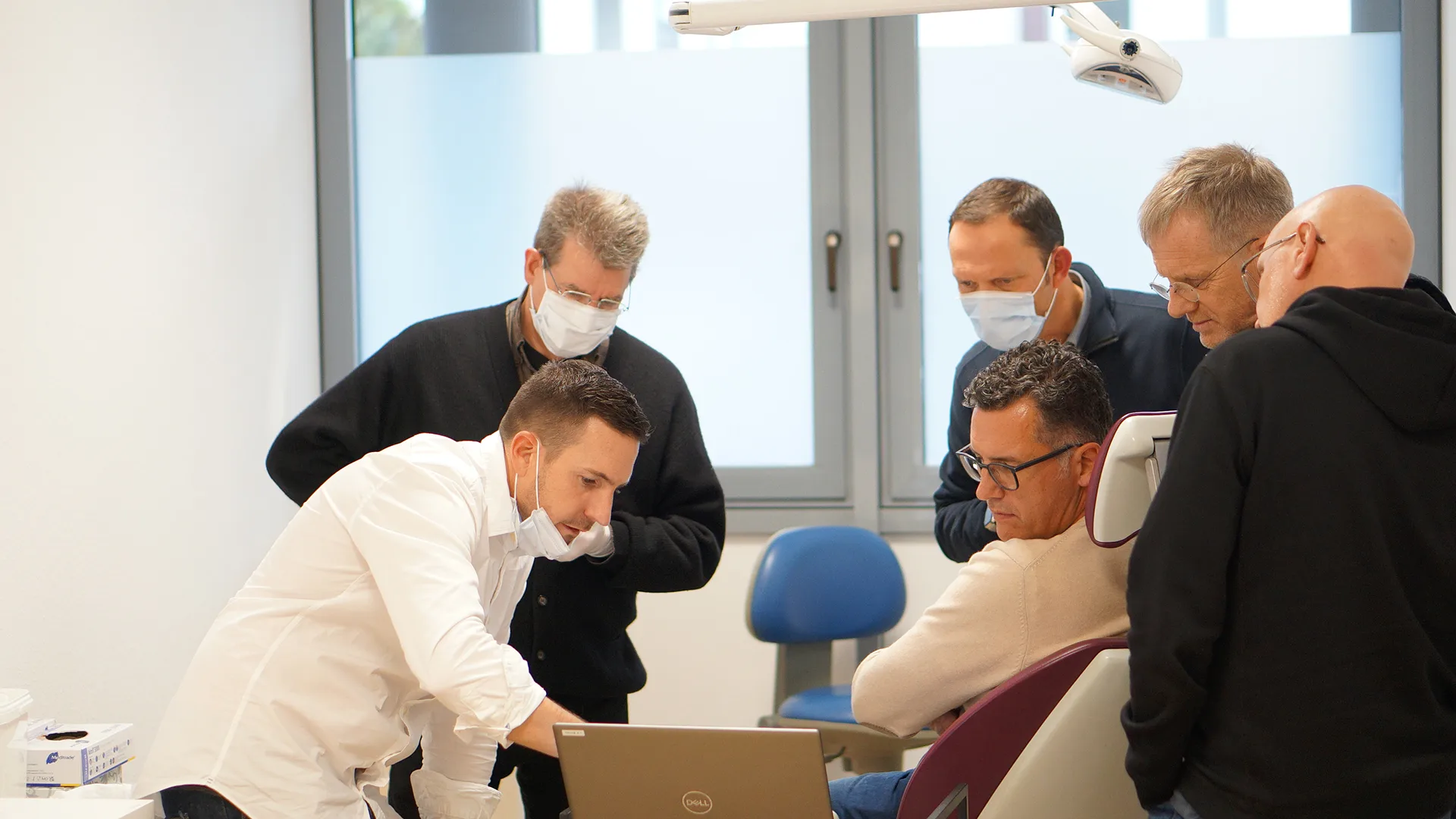 In einem Behandlungszimmer schauen sich mehrere Menschen etwas auf einem Bildschirm an,