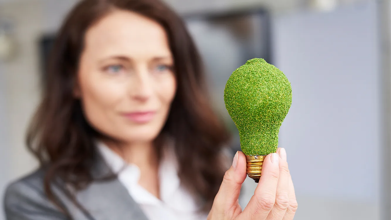 Eine Frau die eine grüne Glühbirne in der Hand hält.