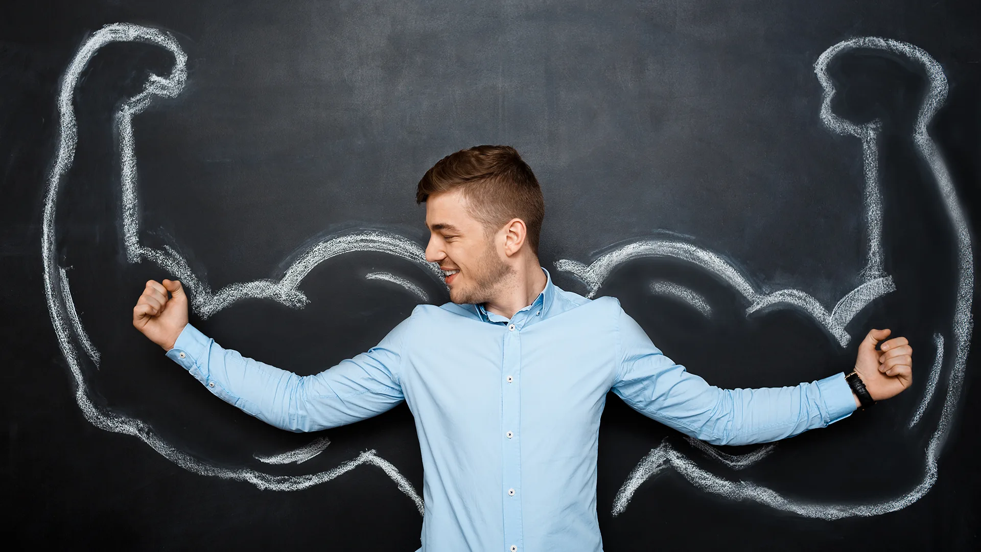 Ein Mann der seine Muskeln anspannt vor einer Tafel.