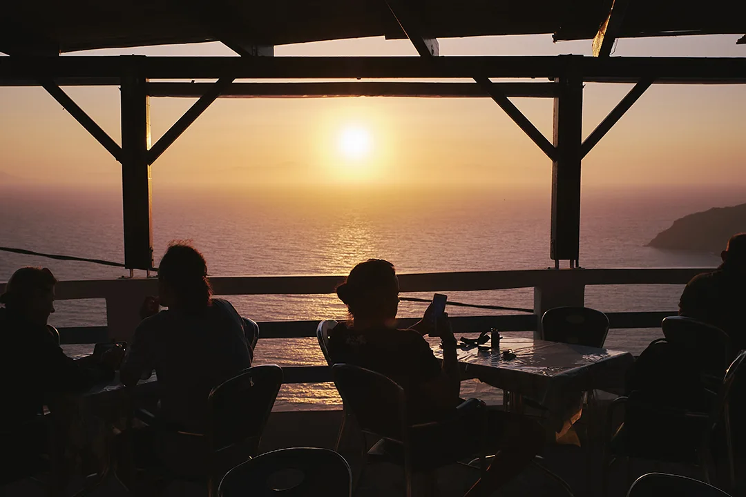A silhouette of people enjoying their time at sunset in a cafe at Potamos beach, Greece