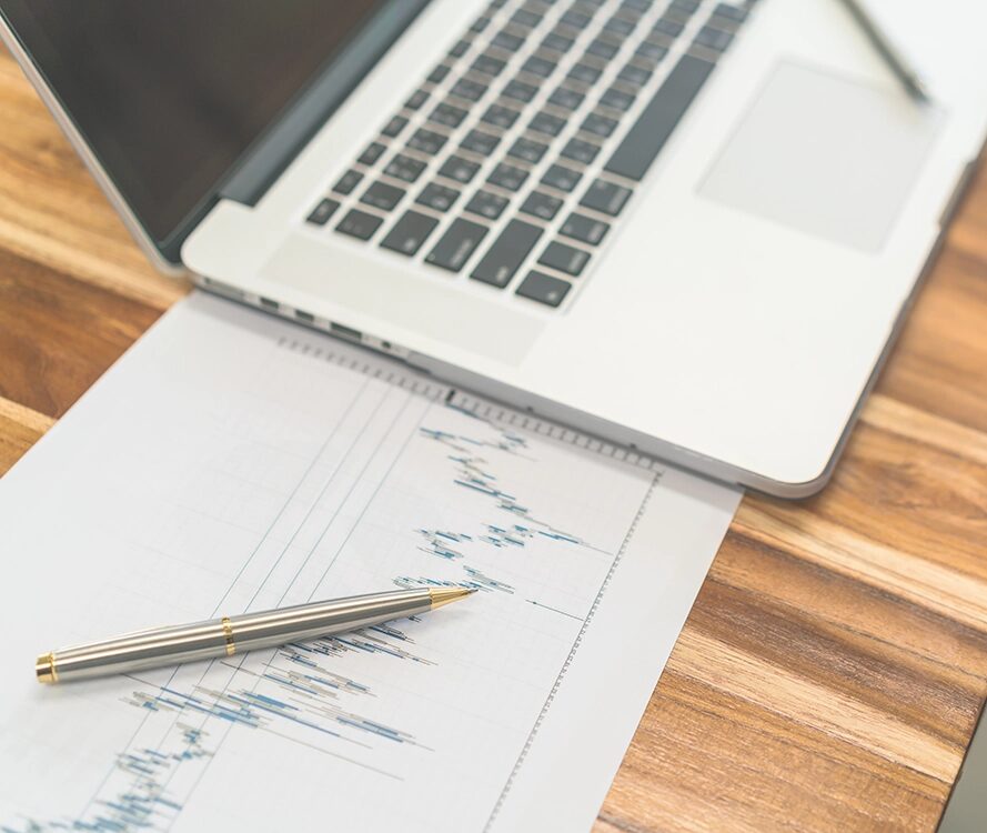 offener Laptop, daneben Auswertungen.