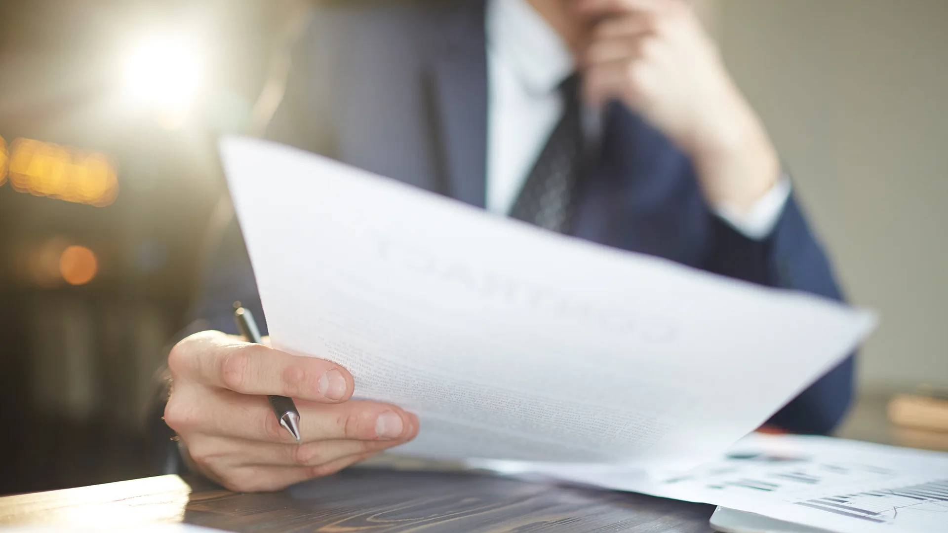 Ein Mann hält ein Dokument und einen Kuli in der Hand.