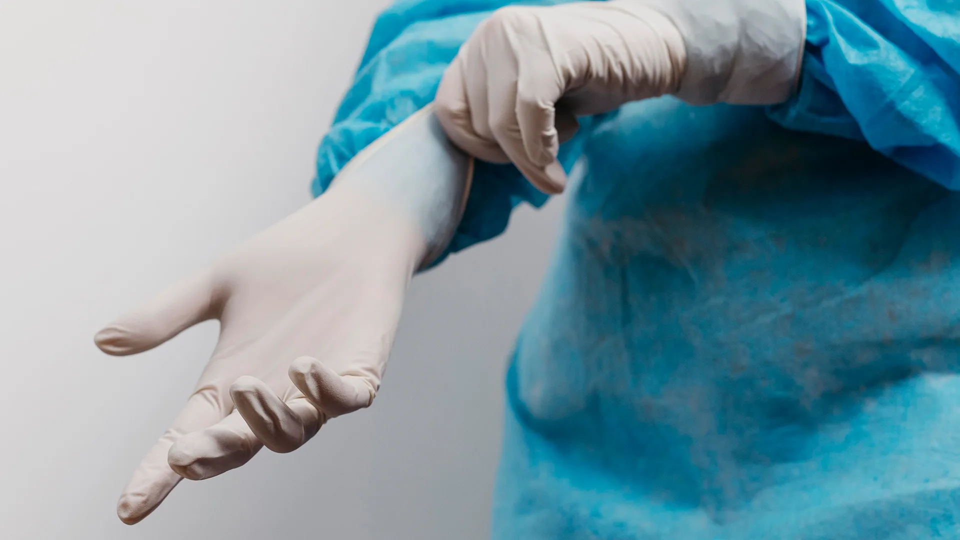 Ein Arzt der einen Handschuh zum Operieren anzieht