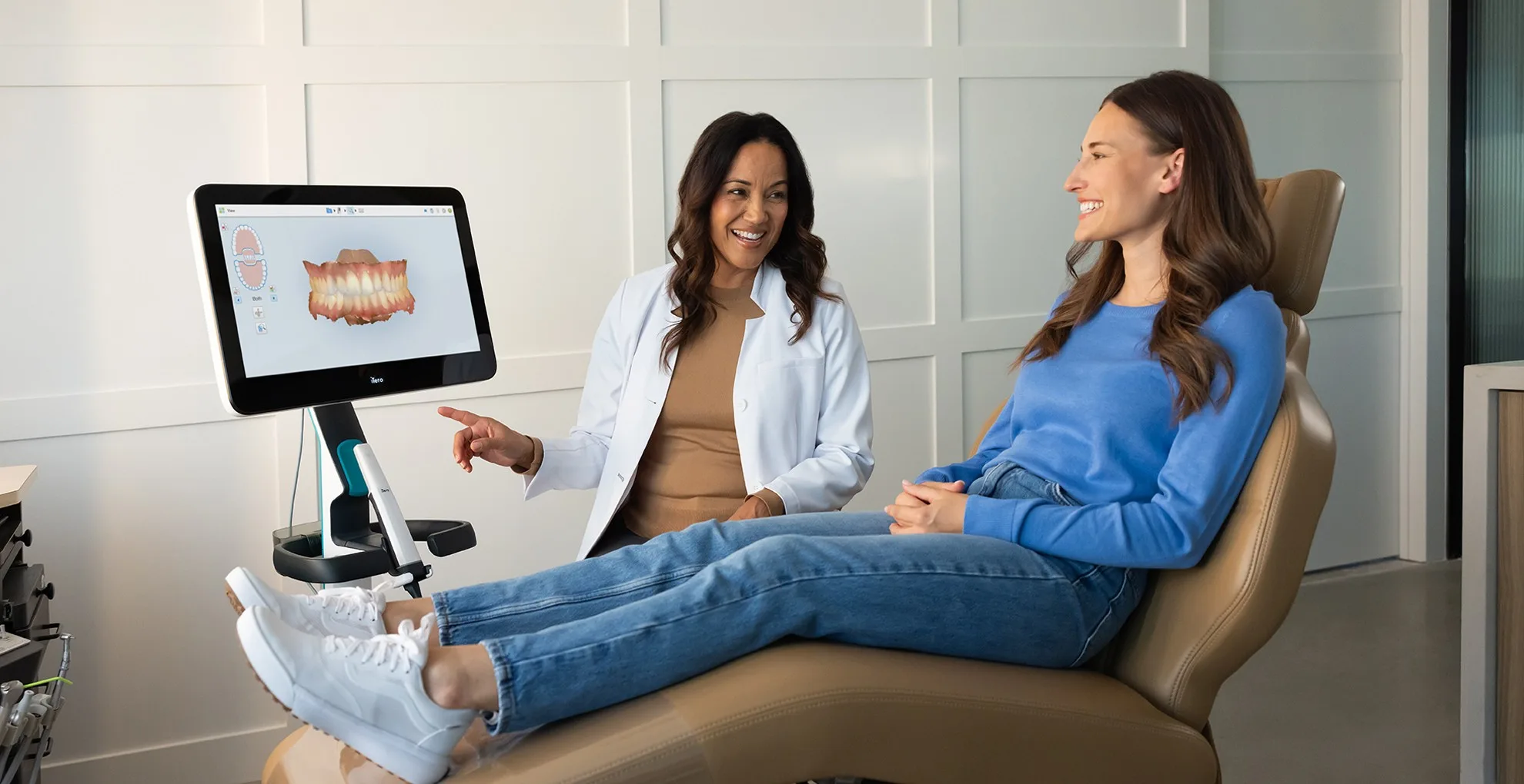 Zahnärztin ihrer Patientin an einem Bildschirm eine Behandlung.