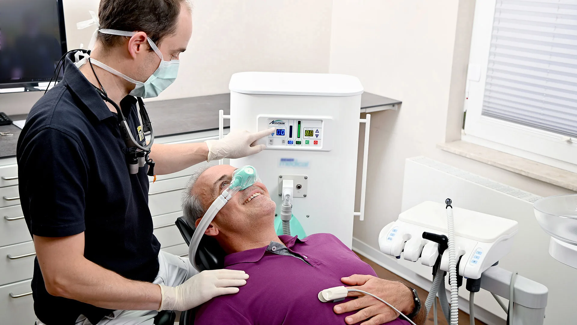 Ein Zahnarzt sediert seinen Patienten im Behandlungszimmer mit Lachgas.