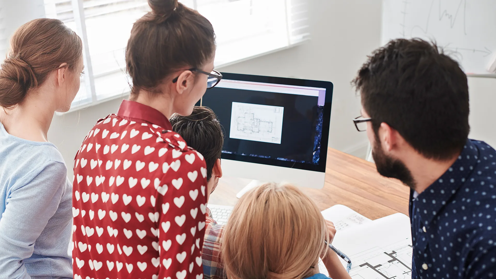 eine Gruppe junger Menschen schauen zusammen auf den Bildschirm.