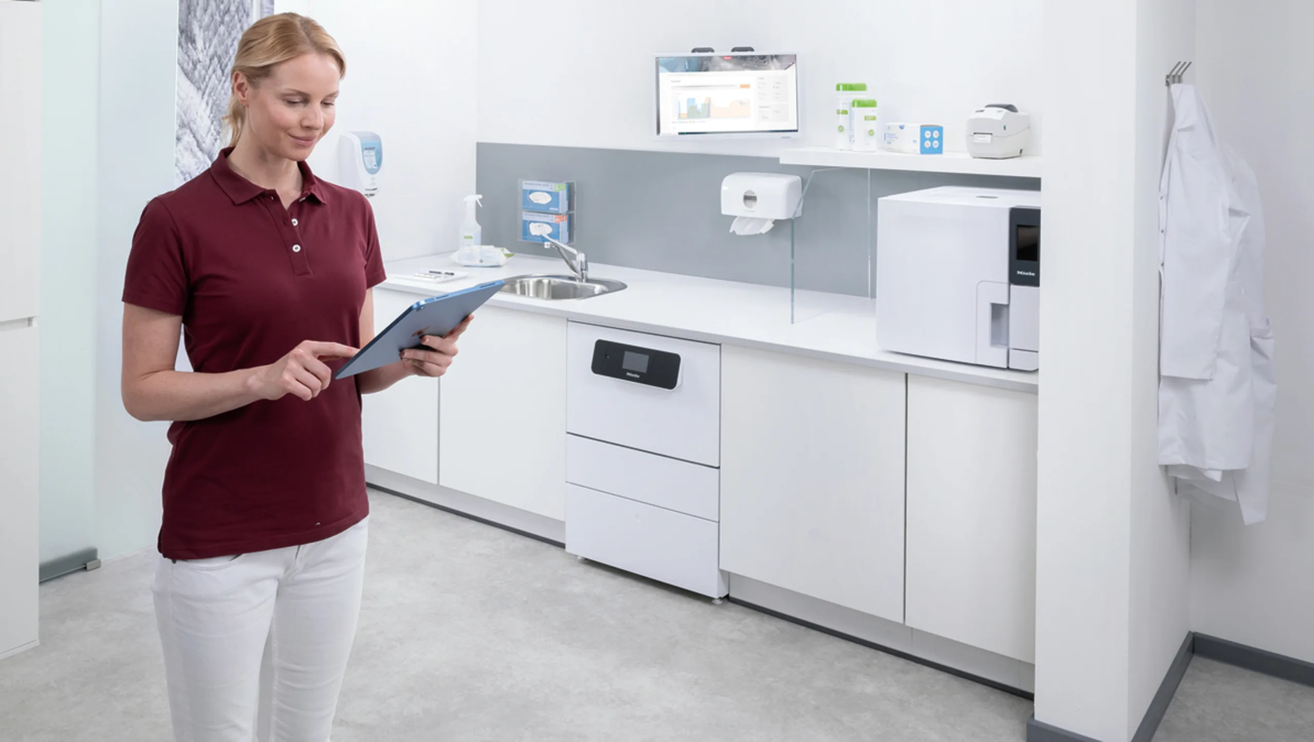 Mitarbeiterin steht mit einem Klemmbrett in einem Raum Reinigungs- und Desinfektionsgeräten und prüft etwas.