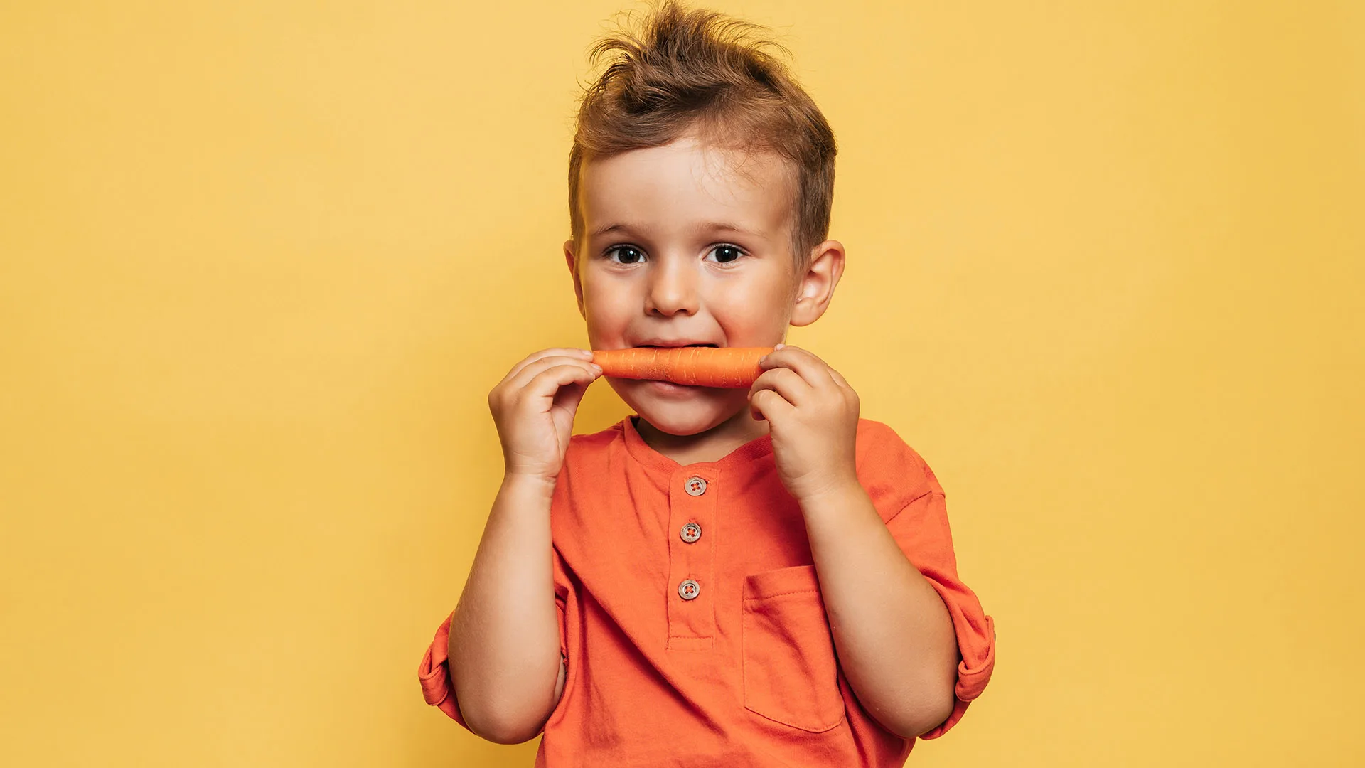 Ein Kind isst eine Karotte.