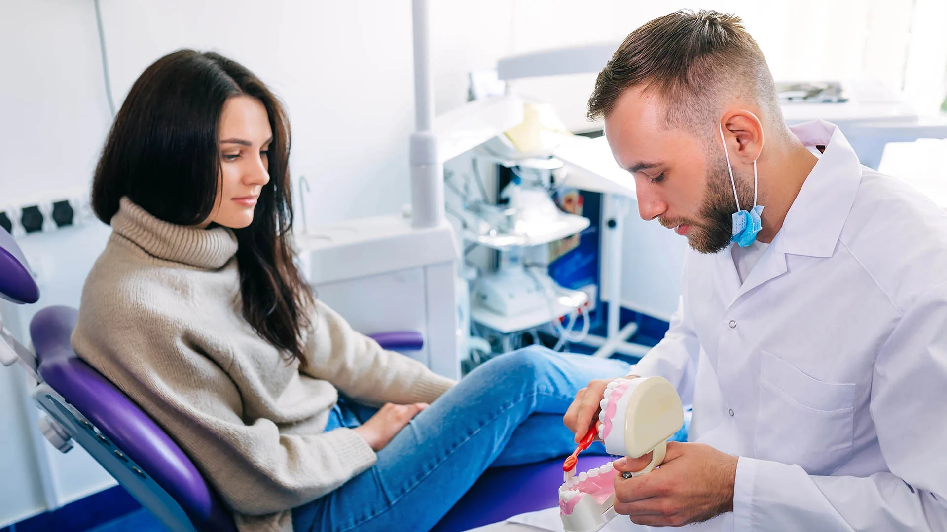 Frau in einem Behandlungszimmer. Arzt zeigt ihr wie man eine Prothese reinigt.