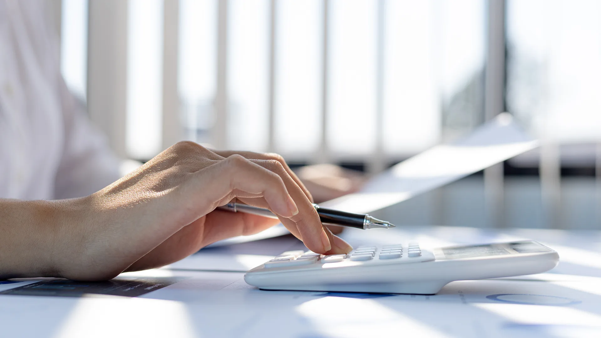 von einer Frau die Hand die den Taschenrechner bedient.