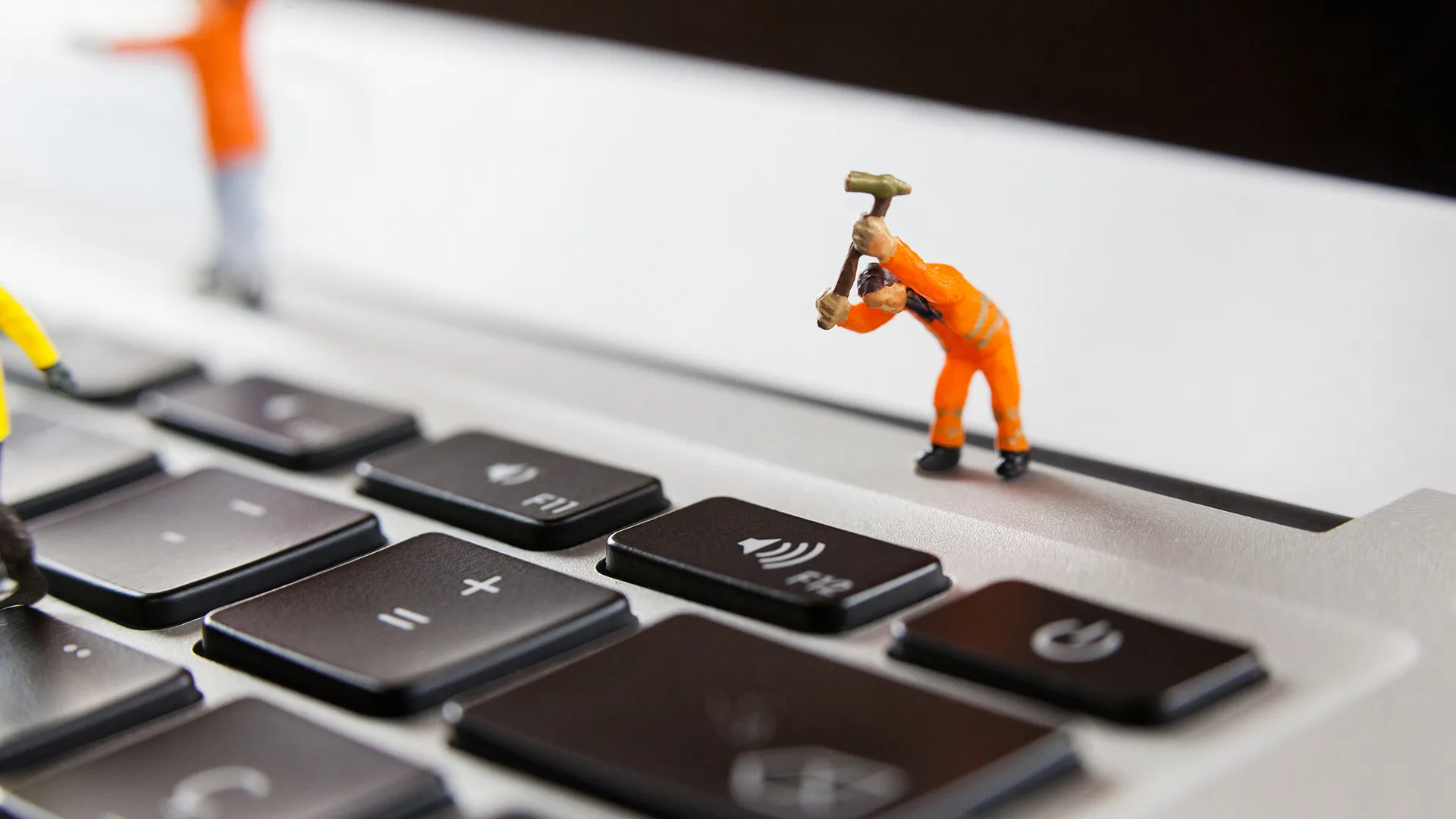 Eine kleine Spielfigur repariert einen Laptop.