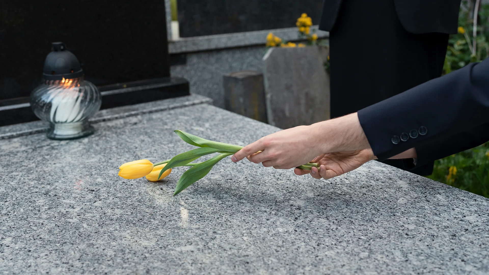 Eine Frau legt eine Tulpe auf ein Grab.