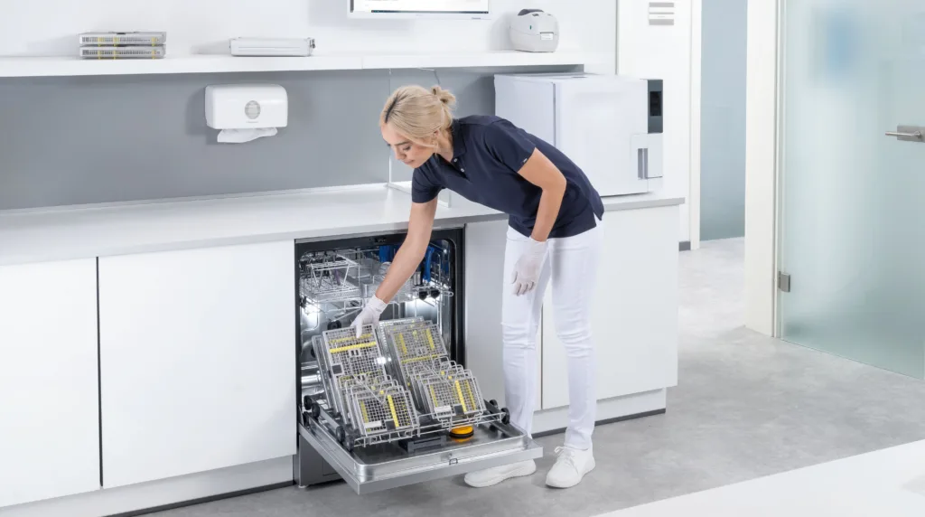 Mitarbeiterin räumt die ExpertLine Dental von Miele mit Instrumenten etc. zur Aufbereitung ein.