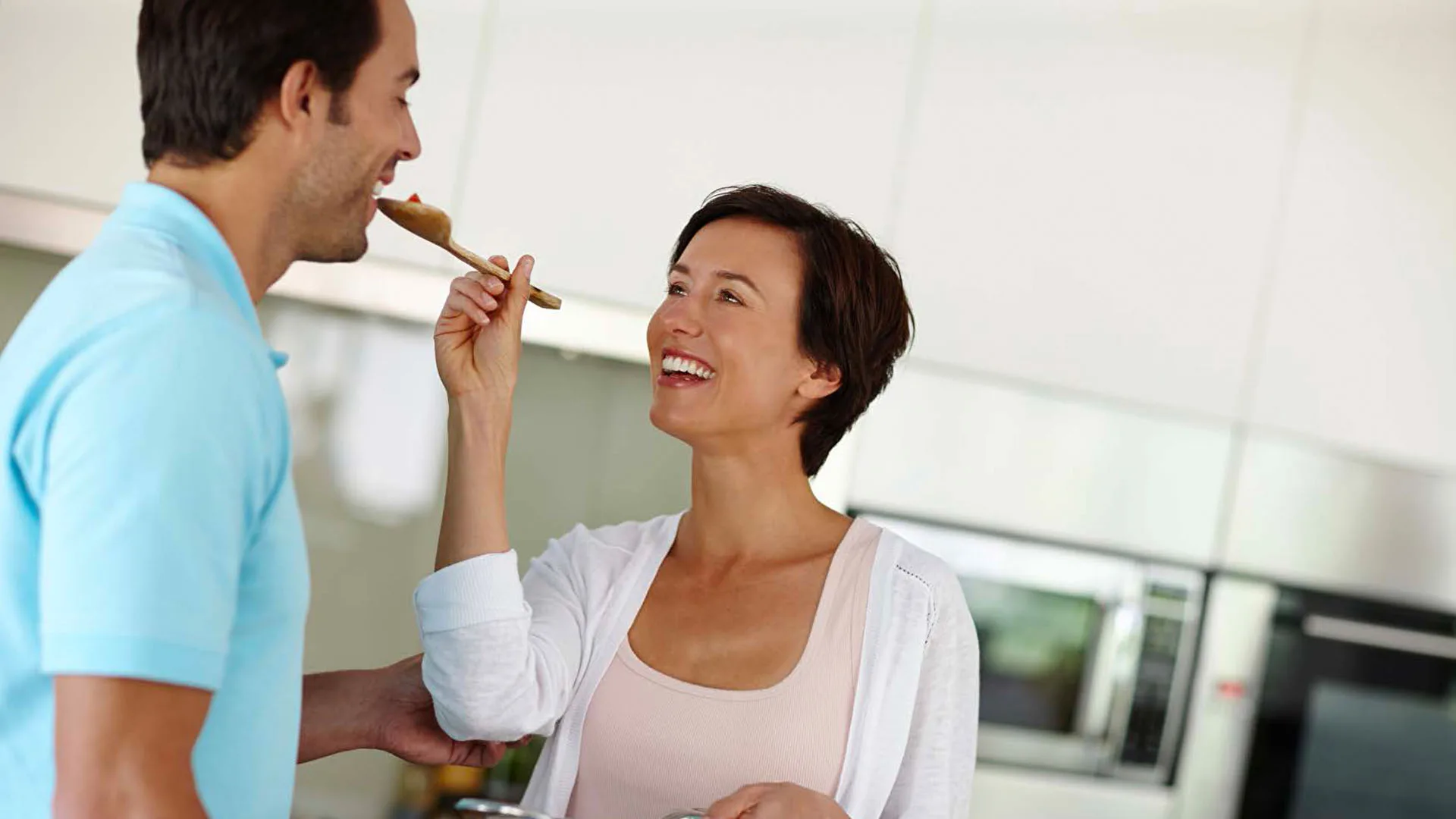 Eine Frau lässt ihren Mann lachend ihr Essen probieren