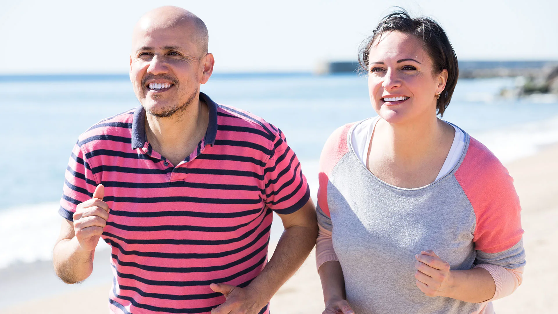 Ein Mann und eine Frau joggen am Strand.