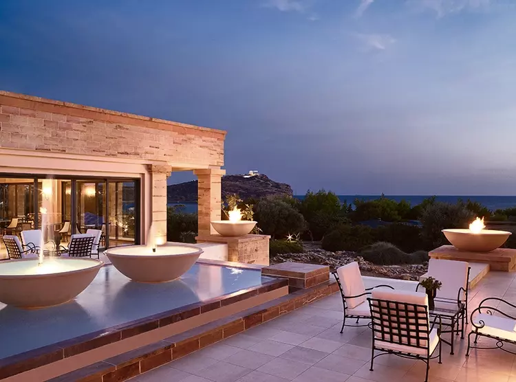 Sitzplatz neben Brunnen und Feuerschale mit Blick auf die Aegaeis und den Poseidon-Tempel.