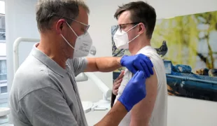 Beim ersten Impftermin in der Praxis lässt sich Dr. Patrick Putze die Auffrischimpfung von seinem Vater geben.